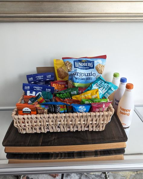 Pantry snacks and food items collected in a basket and placed on a table Happy Apartment, Hospitality Baskets, Pantry Snacks, Guest Basket, Snack Basket, Walkers Shortbread, Office Snacks, Mexican Snacks, Grain Free Granola