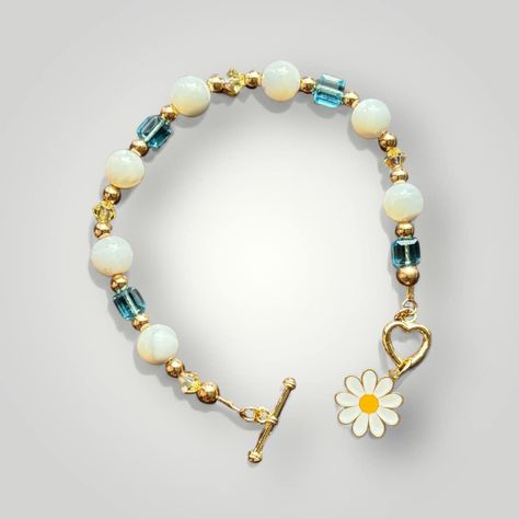 $54.99 Dreaming of warm spring and summer days and beautiful flowers. This Daisy & heart shaped gold toggle bracelet is made on 14k gold filled chain with 8mm natural Mother of Pearl stones, Swarovski crystals in both Capri Blue faceted glass bead and 5mm Jonquil yellow aurora borealis glass beads with gold hematite accents! Mother of Pearl A protection stone, Mother of Pearl brings the gentle healing power of the sea. It is a stress relieving stone; relaxing, soothing and calming to the ... Daisy Heart, Yellow Bracelet, Beads Ideas, Warm Spring, Bracelet Design, Protection Stones, Toggle Bracelet, Healing Power, Capri Blue