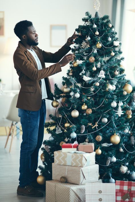 A well-dressed man decorating the Christmas tree next to gifts Christmas Tree Photos, Christmas Tree Photoshoot, Christmas Tree At Home, Decorating Christmas Tree, Decorating The Christmas Tree, Tree Photos, Christmas Tree Images, Photography Men, Single Man