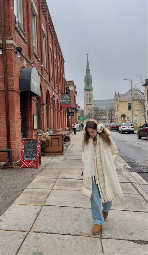 cream long puffer jacket and uggs and chunky white scarf with earmuffs scandinavian style and light wash jeans girl walking down road in European small town city White Puffer Jacket Outfit Winter, Cream Scarf Outfit, Cream Puffer Jacket Outfit, Long Puffer Coat Outfit, White Scarf Outfit, Puffer Jacket Outfit Winter Style, Cream Jacket Outfit, White Puffer Jacket Outfit, Long Puffer Jacket Outfit