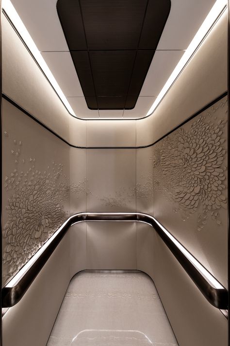 Having a home elevator in itself is a luxury but this lavish elevator design brings the personal lift to a whole new level. Instead of cramping in layered textures and colors, the design opts for a monochromatic approach while not failing to add a unique flair with intricate swirls of petals. Of course, the signature curved ceiling and corners are integrated to create a more relaxed atmosphere, with cool lighting that lends a calming effect while flattering the neutral hues. Lift Lobby Design, Elevator Lobby Design, Curved Ceiling, Home Elevator, Elevator Interior, Luxury Mansions Interior, Elevator Lobby, Modern Luxury Interior, Luxury Hospitality