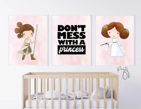 Three framed pink prints hang on a white wall above a wooden crib. The left frame features an illustration of Rey holding her staff. The middle frame features the words “Don’t Mess with a Princess”. The right frame features an illustration of Princess Leia in her New Hope white dress and classic hair buns holding a blaster. Star Wars Nursery Girl, Star Wars Baby Room, Marvel Nursery, Star Wars Leia, Decoracion Star Wars, Kids Room Printables, Star Wars Baby Shower, Star Wars Nursery, Superhero Nursery