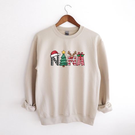 A "Nana Christmas sweatshirt" refers to a Christmas-themed sweatshirt specifically designed for grandmothers, often with the word "Nana" printed on it. The term "Nana" is a popular, affectionate term for a grandmother, so the sweatshirt typically celebrates the holiday season while honoring the special role of a grandmother in the family. These sweatshirts often feature fun and festive designs, such as Christmas trees, Santa, reindeer, or holiday greetings, combined with the term "Nana" to make the garment personalized and meaningful for grandmothers during the Christmas season. They make great gifts for grandmothers to wear during the holidays! A sturdy and warm sweatshirt bound to keep you warm in the colder months. A pre-shrunk, classic fit sweater that's made with air-jet spun yarn for