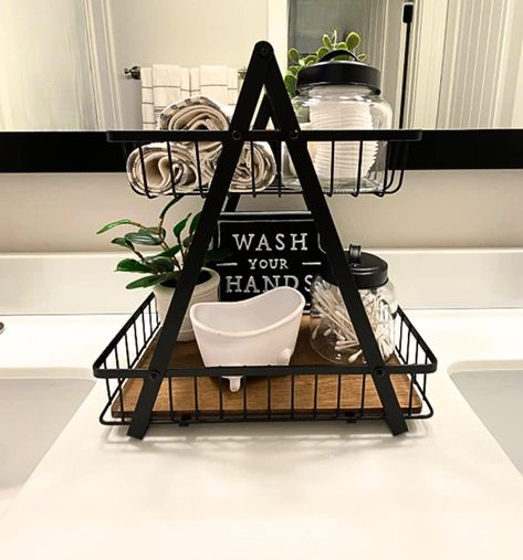 "This multi-purpose, Farmhouse-style countertop organizer is an attractive decorative accent and an effective organizer for the bathroom or any room of the house! This best-seller has more than 75, 5-star reviews!  The rustic Two-Tier Decorative Basket will elevate your bathroom counter however you style it. Check out the reviews for inspiration from our customers who love to fill it with rolled towels, filled jars, cosmetics, lotions, candles, small plants and decorative signs.  DETAILS Dimensi Farmhouse Bathroom Vanity Decor, Towel Organizer Bathroom, Airbnb Towel Storage, Above Toilet Towel Storage, Bathroom Basket Decor, Bathroom Setup Ideas, Black And White Bathroom Decor Ideas, Bath Towel Storage Ideas, Decorate Bathroom Ideas