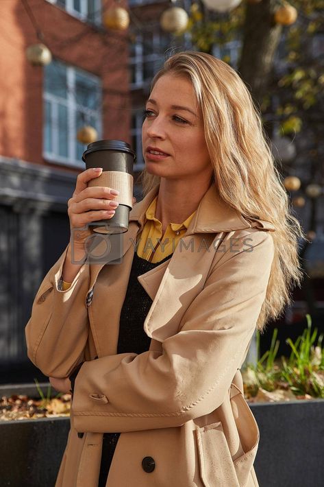 caucasian attractive woman in beige trench coat holding cup of coffee outdoors #Ad , #holding, #cup, #coffee, #outdoors Woman Holding Coffee Cup, Person Holding Soda Can Reference, Life Model Reference, Holding Coffee Pose Reference, Person Holding Coffee Reference, Holding Cup Pose Reference, Coffee Pose Reference, Holding Coffee Reference, Holding Coffee Cup Reference