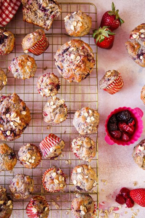 A cooling rack with a whole bunch of berry oat muffins on a pink background Berry Breakfast Muffins, Healthy Berry Muffins, Blackberry Muffins Healthy, Oat Fiber Muffins, Protein Berry Muffins, Berry Oat Muffins, Mixed Berry Oatmeal Muffins, Raspberry Oat Muffins, Strawberry Oat Muffins