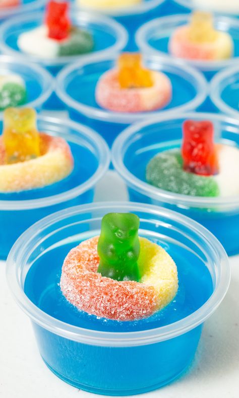 9 2oz plastic containers filled with bright blue jello topped with a candy gummy bear and gummy ring. Ocean Water Jello Shots, Pool Party Jello Shots, Jello Shots With Vodka, Shots With Vodka, Party Jello Shots, Vodka Jelly, Vodka Gummy Bears, 34 Birthday, Candy Rings