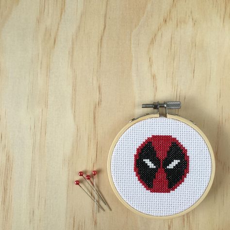 Deadpool fans this one is for you. Wade Wilson never looked so good than in the cross stitched form!  All those over 18s who loved the film and everyone who loved the comics this captures the iconic mask of the super sassy super hero Deadpool.  While you wait for the second film to come out this little number should be proudly on display in your comic book nerd collections!  Measuring 9cm in diameter this piece has been hand sewn and sealed with felt to lock in all the super stitching powers! Deadpool Cross Stitch Pattern, Deadpool Cross Stitch, Deadpool Embroidery, Crown Frames, Deadpool Logo, Wade Wilson, Framed Cross Stitch, The Cross, Super Hero