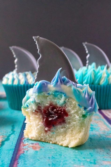 Shark Week Cupcakes are easy to make, fun to eat and the perfect sweet treat to sink your teeth into. Homemade orange cupcakes filled with a bite of rasberry orange sauce, these Shark Week Cupcakes are great for viewing parties, days at the beach or watching your favorite shark show on TV. | A Wicked Whisk #sharkweekcupcakes #sharkweekfood #sharkweekparty #sharkweekfoodideas #sharkweekfoodrecipes #sharkweekdesserts #sharkattackcupcakes Shark Week Cupcake Ideas, Diy Shark Cupcakes, Shark Theme Cupcakes, Shark Week Cupcakes, Shark Cupcakes Kid Birthdays, Shark Pull Apart Cupcakes, Shark Week Desserts, Jaws Cupcakes, Shark Birthday Cupcakes