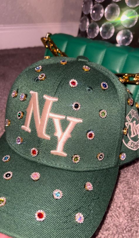 Adjustable NY Custom Bedazzled Hat customed by ShanayCosmetics Comes in 2 colors: Black or Green More colors COMING SOON....  PLEASE KEEP IN MIND THAT I AM NOT RESPONSIBLE FOR ANY DELAYS WITH SHIPPING ONCE I HAVE DROPPED YOUR PACKAGE OFF AT THE POST OFFICE! THAT IS OUT OF MY CONTROL. PLEASE BE AWARE I AM NOT RESPONSIBLE FOR ANY LOST, DAMAGED OR STOLEN PACKAGES!! Custom Ny Hat, Pearl Fitted Hat, Beaded Graduation Cap, Diy Leather Hat, Bedazzled Hat, Custom New Era Hats, Customized Hats, Bedazzled Stuff, Swag Items