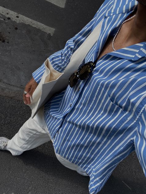 selfie from a bird’s eye view of a guy wearing a blue button up shirt with white vertical stripes, cream color baggy jeans, white sneakers and a cream color tote bag. Sunglasses, a chrome ring and an asymmetrical pearl necklace are used as accessories. Mens Blue Striped Shirt Outfit, Blue Button Up Outfit Men, Blue Shirt Outfit Men Aesthetic, Blue White Stripes Shirt Outfit, Blue Button Down Shirt Outfit Men, Blue And White Striped Shirt Outfit Men, Blue Button Up Shirt Outfit Men, Blue Striped Shirt Outfit Men, Longsleeves Outfit Men