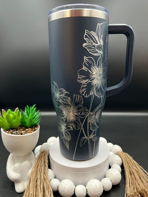 Wildflowers Floral Laser Engraved 40oz Tumbler with Handle Lid and Straw, Custom Engraved Seamless Tumbler, Double Wall Insulated Cup This custom engraved 40oz Powder Coated Double Wall Insulated tumbler with handle and leak proof lid keeps you beverage at the perfect temperature for hours!  **TUMBLER IN PHOTO IS TO ILLUSTRATE THE DESIGN OPTION.  IT MAY BE SHOWN ON A BRAND     TUMBLER BUT DOES NOT REPRESENT THE TUMBLER YOU WILL RECEIVE.  IF YOU ORDER NON     BRANDED, YOU WILL RECEIVE A NON BRAND Etched Stanley Cup, Laser Engraving Cups, Engraved Tumbler Designs, Laser Engraved Cups, Laser Engraved Tumblers, Stanley Ideas, Etched Tumblers, Yeti Cup Designs, Stanley Brand