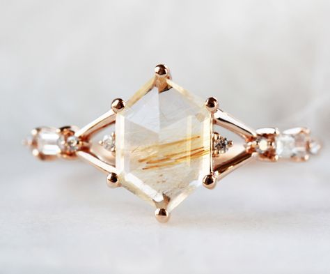 This Ring: Material: 14K Solid Gold Gemstone: Hexagon Rutilated Quartz x 1 piece (~1.35ct) SI/G Baguette 3 x 1.5mm 2 pieces (0.08ct) VS/G 1mm Diamond x 4 pieces (0.02ct) You can choose different Main stone and also modify the settings. Design your engagement ring. Choose the Main stone Select this setting style to build your engagement ring Recommend matching band to this ring Engagement_Little tiara matching band Eccentric Engagement Ring, Hexagon Engagement Ring With Band, Nontraditional Engagement Rings Vintage, Unique Gemstone Rings, Non Traditional Engagement Ring, Not Diamond Engagement Rings, Non Diamond Engagement Rings Gemstone, Untraditional Wedding Rings, Gem Stone Engagement Rings