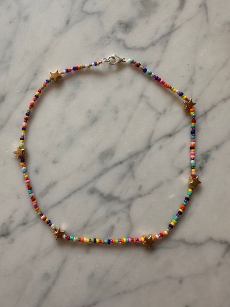 This is a handmade, colorful,  necklace. There is a clasp to take on and off and unique gold star beads. Homemade Necklaces, Flat Beads, Star Beads, Bead Tutorials, Colorful Necklace, Diy Jewelry Unique, Pulseras Diy, Seed Bead Tutorial, Beaded Bracelet Patterns