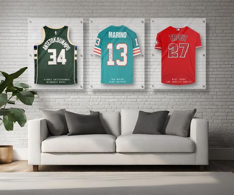 Protect your prized sports jersey with this custom personalized handmade acrylic display frame case. Each storage frame is handmade with 3 panels of ultra-clear 4mm thick high-grade acrylic that is UV-protecting and clear as glass. Each case is made up of 3 stacked acrylic panels. The center panel has a built-in hanger and provides the open spacing for the jersey to be protected from dust. The panels are stacked and locked in place with a series of 6 metal standoffs which then secure easily to y Framed Sports Jersey, Jersey In Frame, Framing A Jersey, Jersey Frame Ideas Display Case, Sport Memorabilia Display Wall, How To Display Jerseys On Wall, How To Frame A Jersey, Diy Jersey Display Case, Framed Jerseys On Wall