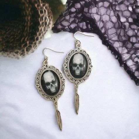 https://www.etsy.com/listing/1379091360/skull-earrings-gothic-gift-for-her 💀🖤 Embrace the dark allure with our Metallic Skull Feather Gothic Earrings! These occult witchcraft earrings for women are more than just accessories—they're statements of gothic beauty and mystique. With their metallic skull and feather design, they exude an aura of dark style and sophistication, making them perfect for lovers of gothic jewelry and spooky accessories. 🌙🔮 Let these earrings serve as a symbol of your ... Spooky Accessories, Pagan Symbols, Earrings Gothic, Gothic Gifts, Alternative Jewelry, Dark Style, Gothic Earrings, Gothic Beauty, Feather Design