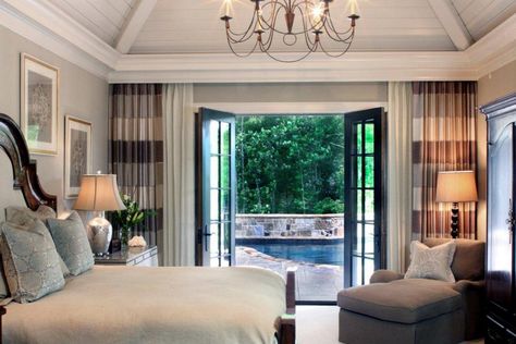 This transitional master bedroom features French doors that open to the pool, which create a private resort-like feel. Wall-to-wall curtains add texture and interest as well as draw the eye to the doors and out onto the patio. Vaulted ceilings and a stunning chandelier add drama and height to this cozy space. Bedroom Patio Doors, Bedroom French Doors, Master Suite Addition, French Doors Bedroom, Bedroom Addition, Bedroom Patio, Storage Inspiration, Neutral Bedrooms, French Doors Patio