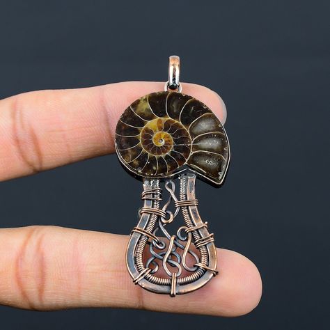 Welcome to our little shop, where you can find handmade copper wire jewelry and more, for you and your loved ones. We do accept custom orders also, kindly message us for more. Ammonite Fossil Gemstone Copper Wire Wrapped Handmade Pendant A copper I wrapped on a beautiful Ammonite Fossil Gemstone . Size May Be slight Differ Than Shown In The Picture Gemstone : Ammonite Fossil  Metal : Copper  * Protection:- Copper will be tarnished after a while so try to limit contact with lotions, soaps or anything moist and never wear it in the shower, swimming or anywhere else it may come in contact with water. If tarnish becomes an issue, you may clean this item with jewelry cleaning cloth or ultra polishing pads. * Packing:- Your jewelry arrived in a beautiful gift box stored in bubble wrap for safe t Wire Wrapped Mushroom, Copper Wire Jewelry, Copper Jewelry Handmade, Fossil Jewelry, Ammonite Fossil, Handmade Jewelry Gift, Handmade Copper, Handmade Pendant, Wrapped Pendant