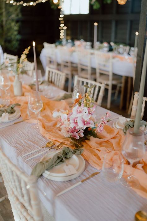 This shows a wedding tablescape, inspired by a wildflower vibe. On the table are light purple tablecloths, a coral orange table runner, a small colourful flower arrangement and neutral white plates with green napkins. There are also tealight and candle holders as decor with LED candles. Purple Tablecloth, Barn Photography, Dinner Setting, Green Napkins, Event Display, Event Backdrop, Food Table, Muslin Fabric, Coral Orange