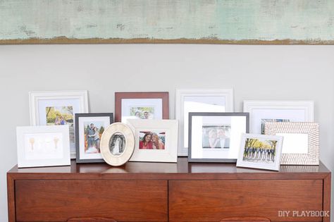 Rookie Mistake: Picture Frames - DIY Playbook How To Display Picture Frames, Sideboard Photo Display, Picture Frame On Table Arranging, Styling Picture Frames On Shelves, Styling Picture Frames On Table, Dresser Picture Display, Layered Frames On Shelf, Wedding Pic Display Home, How To Style Picture Frames On Table