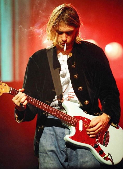 Kurt Cobain smoking a cigarette while onstage during Nirvana’s MTV: Live and Loud concert in 1993. | 23 Iconic Pictures Of Rock 'N' Roll's Greatest Performers Kurt Cobain, Nirvana, Electric Guitar, Long Hair, Guitar, Red, Hair