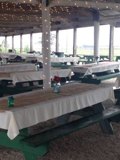 Bride used the existing picnic tables in the pavillion. I softened the look with covers, runners and a simple centerpiece. Lights were added to center poles and ceiling. Driskill wedding decorated by *The Farm*. Pinic Table, Picnic Table Wedding, Pavillion Wedding, Baseball Banquet, Grandmas Birthday Party, Metal Picnic Tables, Simple Centerpiece, Tent Decorations, Picnic Tables