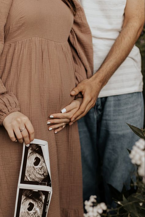 Man holding woman’s hand over her belly over her pink dress, in the womans other hand holds and ultrasound, the picture cuts off right before their heads Things To Do With Ultrasound Pictures, Maternity Shoot With Sonography, Maternity Pictures With Ultrasound, Pregnancy Announcement Pictures Without Ultrasound, Maternity Shoot Ultrasound, Studio Baby Announcement, Maternity Pictures Ultrasound, Maternity Shoot With Ultrasound, Poses With Ultrasound