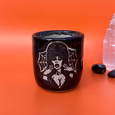 Meet the Elvira Tumbler 🖤✨ Inspired by the iconic Elvira: Mistress of the Dark, this piece brings a touch of gothic glam to your day. Thrown on the wheel with a sleek Mayco Jungle Gems glaze - Black Iris on the outside and a smooth white glaze on the inside—it's perfect for your favourite drinks or simply to admire! What spooky sips would you enjoy from this one? Available now on my Etsy store. Link in bio. #tumblercups #tumblercustom #mistressofthedark #potterylovers #potterylover #handm... Goth Ceramic Art, Goth Tumbler Cup, Goth Mug, Vampire Coffee Mug, Goth Coffee Mug, Gothic Glam, Black Iris, White Glaze, Tumbler Cups