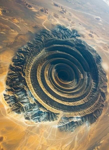 Richat Structure, the "Eye of the Sahara" The Richat Structure, also known as the "Eye of the Sahara," is a prominent circular geological formation located in the Sahara Desert in Mauritania. This distinctive feature, visible from space, resembles a large bull's-eye and is about 40 kilometers (25 miles) in diameter. Initially thought to be an impact crater, it is now believed to be a highly eroded dome of sedimentary rock. The concentric rings of the Richat Structure make it a fascinating su... Eye Of The Sahara, Impact Crater, David Attenborough, The Sahara Desert, Sedimentary Rocks, Sahara Desert, Landscape Photos, Nature Travel, Geology