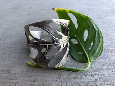 This Monstera Swiss Cheese cuff is hand fabricated with sterling silver sheet and wire. Formed using the heat of my torch, stakes and hammers. It is 2.5" at its widest point and 6" (not including the gap) around.This piece is one of a kind. Sheet Metal Jewelry, Nature Inspired Jewelry Sterling Silver, Dope Jewelry, Swiss Cheese, Funky Jewelry, Nature Inspired Jewelry, Jewelry Lookbook, Jewelry Sterling Silver, Hammers