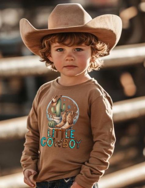 Yeehaw! Saddle up with our charming long sleeve boys' tee that celebrates the adventurous spirit of a 'Little Cowboy'.  It's a perfect addition to any young cowboy's wardrobe, inspiring them to embrace their adventurous side while showing off their love for the great outdoors! Let us be your go-to destination for all your kids' t-shirt needs! Our studio specializes in crafting fun, comfortable, and stylish t-shirts that kids will love to wear. Each shirt is made to order, ensuring a perfect fit and unique designs that cater to every child's personality. From vibrant colors to playful graphics, we have something for every little one. Trust us to provide high-quality, individually made t-shirts that your kids will cherish and proudly show off! We also have boutiques in Midlothian, Virginia & Country Kids Outfits, Midlothian Virginia, Playful Graphics, Gift Sack, Fall Family Pictures, Little Cowboy, Country Kids, Cowboy Outfits, Western Aesthetic