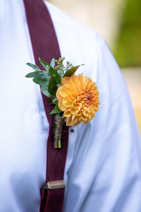 The perfect fall boutonniere is undoubtedly incorporates a dahlia. In this boutonniere, we used an orange dahlia with bits of eucalyptus and ruscus. Dahlia Boutonniere Wedding, Dahlia Boutonniere, Bridgerton Garden Party, Bridgerton Garden, Yellow Boutonniere, Fall Boutonniere, Simple Boutonniere, Orange Boutonniere, Dahlia Wedding Bouquets