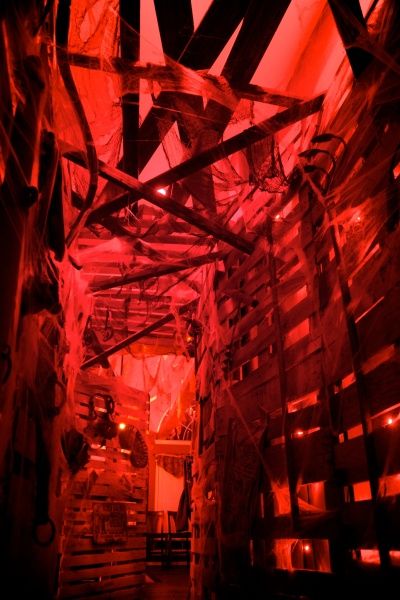 Pallet board walls, gauze, web, & red back lighting.  Nice effect. Haunted House Zombie Room, Haunted Prison Theme, Haunted House Attraction Aesthetic, Creepy Theater, Haunted House Layout, Slasher Party, Haunted Theater, Halloween Haunted House Ideas, Haunted Palace