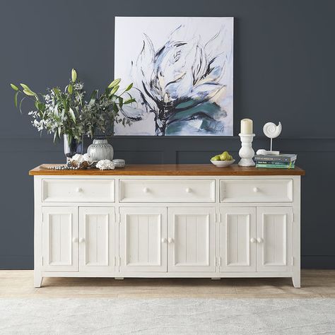 Our two-tone Newport sideboard is made from carefully chosen solid, reclaimed pine shipping pallets with an inlaid timber bow detail on the top corners. It is finished with a honey-coloured stain and our signature ivory wash. The overall finish is achieved through a series of steps: sanding, staining and sealing. This is followed by hand-rubbing with beeswax and natural oils to enhance the look and feel of each product. Nail holes, timber knots, colour variations and timber block patches are common and are not considered a fault. This French country style sideboard works beautifully with timber floorboards and can be mixed and matched with any products from our Tuscan collection. This generous sideboard has enough room for virtually all of your storage needs. Fully assembled. 2100W x 450D Country Style Sideboard, Buffet Styling, Timber Sideboard, Country Style Furniture, Buffet Decor, Shipping Pallets, Large Sideboard, Reclaimed Pine, Nail Holes