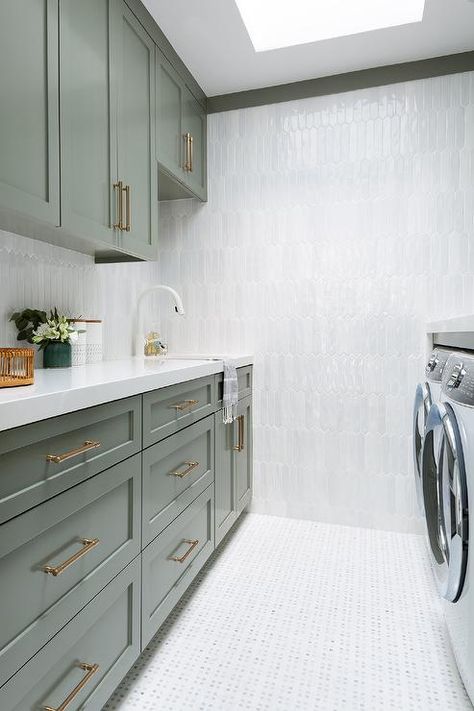 Green shaker laundry room cabinets with white and gray marble picket tiles styled with a white quartz countertop boasting a white gooseneck faucet illuminated by natural light from a skylight. Light Gray Laundry Room, Gray Laundry Room, Yellow Laundry Rooms, Transitional Laundry Room, Grey Laundry Rooms, Blue Laundry Rooms, White Laundry Rooms, Green Laundry, Grey Shelves