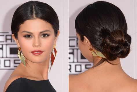 At the 2014 American Music Awards, actress and singer Selena Gomez paired her sleek black gown with a mega-sized 'do perfect for showing off her on-trend center part and oversize gold geometric earrings.  - GoodHousekeeping.com Sock Bun Hairstyles, Center Part Hairstyles, Selena Gomez Hair, Man Bun Hairstyles, Wedding Hairstyles And Makeup, Low Bun Hairstyles, Sleek Bun, Center Part, Low Bun