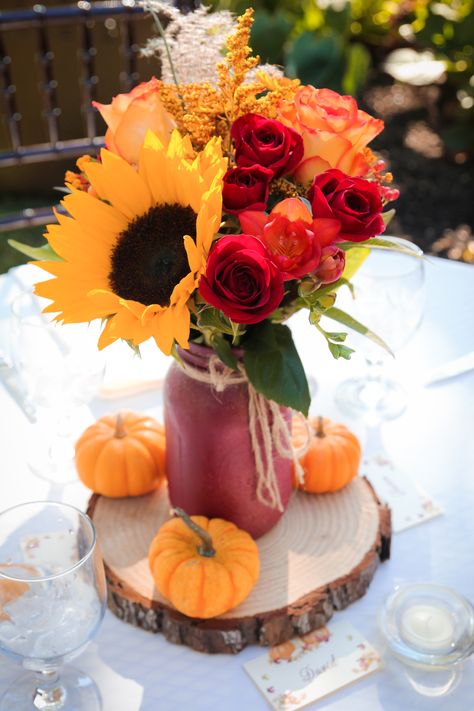 These outdoor fall wedding reception centerpieces included bright sunflowers, red roses, and other seasonal flowers alongside mini pumpkins and rustic wood pieces. This photo was taken by Megan Leigh Photography at one of our real fall weddings located at @josephamblerinn. Fall Wedding Centerpieces Sunflowers, Fall Bridal Centerpieces, Pumpkin And Sunflower Wedding Fall Decorating, Fall Wedding Decor With Sunflowers, Fall Decor For Wedding Receptions, Sunflower And Rose Centerpieces Diy, Pumpkin Sunflower Centerpiece, October Wedding Sunflowers, Sunflower Red Rose Wedding Decor