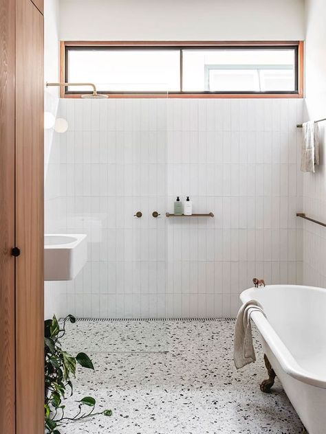 a mid century modern neutral bathroom with skinny tiles, a terrazzo floor, a clawfoot tub, a clerestory window that brings some light Terrazzo Bathroom, Brick Living Room, Subway Tile Design, Terrazzo Floor, Subway Tiles Bathroom, Neutral Bathroom, Tile Layout, Clerestory Windows, Terrazzo Flooring