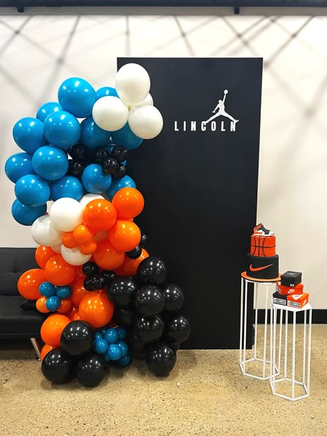 Jordan and Nike inspired birthday party setup with large wooden panel, custom vinyl, balloon garland and cake stands Nike Basketball Birthday, Jordan Basketball Birthday Party Ideas, Nike Balloon Garland, Air Jordan Birthday Party Ideas, Jordan Themed Birthday Party, Basketball Balloon Garland, Nike Theme Party Birthdays, Nike Party Decorations, Nike Theme Party