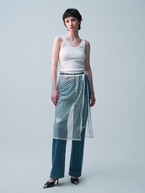 This product is an innovative lace wrap skirt that overlays a pair of classic jeans, offering a unique blend of textures and styles. The skirt features a delicate lace pattern with a translucent appearance, adding a layer of sophistication and visual interest. It ties at the waist with a sleek, adjustable ribbon, allowing for a customized fit while highlighting the contrast between the rugged denim and the refined lace. - This skirt features a distinctive lace design that wraps around and ties at the waist, providing a versatile and adjustable fit.- The lace is designed with an intricate pattern that adds a touch of elegance and complexity to the overall appearance.- Paired with rugged denim jeans, the lace offers a striking contrast that blends casual and upscale fashion elements.- T Lace Skirt Over Jeans, Skirt Jeans Outfit, Rugged Denim Jeans, Asymmetrical Skirt Outfit, Skirt Over Jeans, Wrap Skirt Outfit, Lace Trend, Lace Outer, Upscale Fashion