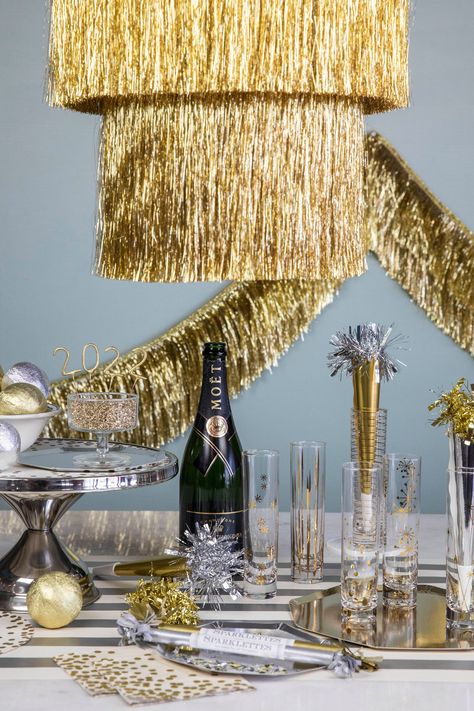 A table with a champagne bottle and glasses, adorned with Meri Meri's Gold Tinsel Chandelier. Tinsel Chandelier, Holiday Event Decor, Golden Birthday Parties, Gold Party Decorations, Tinsel Garland, Golden Birthday, Glam And Glitter, Gold Tree, Fancy Party