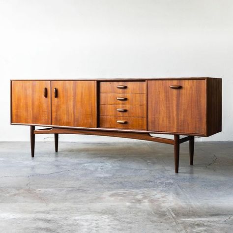 Mid-Century Modern Furniture on Instagram: "G-Plan Fresco, teak, British sideboard designed by V.B. Wilkins.⁠ ⁠ Features:⁠ ⁠ • Beautiful teak woodgrain through-out⁠ • Drop-down bar⁠ • Center drawers⁠ • Doors open to an open fixed shelf⁠ • Model 4058⁠ • Body stands on a frame of turned legs joined by an arched crossbar⁠ • Sculpted teak hardware⁠ • Ample storage⁠ ⁠ Dimensions:⁠ 81“W x 31”H x 18“D⁠ ⁠ Visit the website to learn more and/or to get a shipping quote.⁠ ⁠" G Plan Furniture, Mid Century Sideboard, Teak Sideboard, Sideboard Designs, Door Opener, Mid Century Modern Furniture, Sideboard, Wood Grain, Modern Furniture