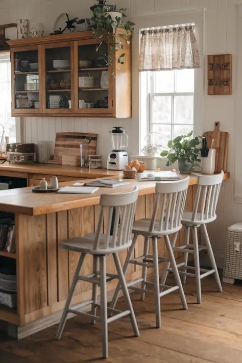 Cozy kitchen with wooden cabinets, a countertop with three stools, plants, and natural light from a window. Counter With Bar Stools, Modern Farmhouse Kitchen Island Stools, Farmhouse Island Seating, Barstools In Kitchen, Farmhouse Style Bar Stools, Small Kitchen Islands, Modern Farmhouse Kitchen Island, Small Kitchen Island Ideas, Metal Stools