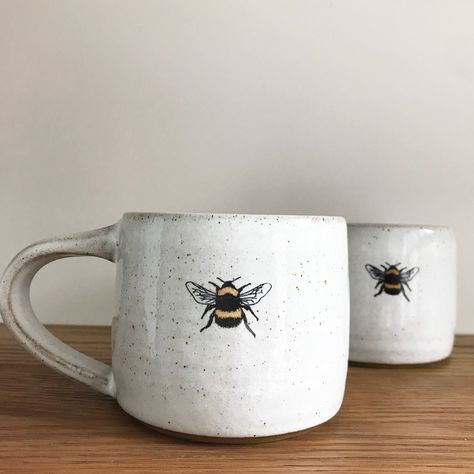 Bumble Bee mug by Heather Mathieson This gorgeous rustic ceramic bee mug has been wheel-thrown using a brown, stoneware clay - glazed with a food safe, glossy white glazeIt features a decal of one of Heather's bumble bee linocut images, which is an original designThe base is unglazed giving a lovely, rich contrast of textures and colours between the glaze and the raw clay bodyEach bee mug is handmade so please expect each one to be different in texture / detail +... Diy Keramik, Mug Diy, Bee Mug, Cerámica Ideas, Pottery Painting Designs, Keramik Design, Rustic Ceramics, Painted Mugs, White Mugs