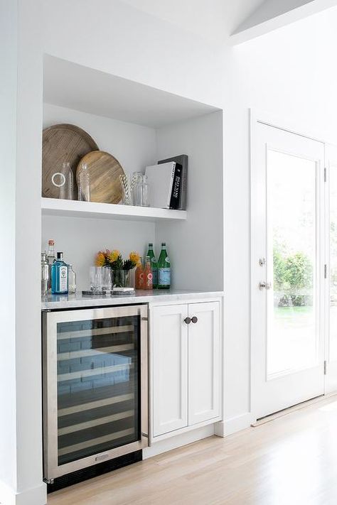 A white styled shelf is mounted in a bar nook above a glass front mini wine fridge fixed beneath a white marble countertop accenting white shaker cabinets contrasted with matte black knobs. Pantry Nook, Wine Fridge Cabinet, Mini Wine Fridge, Bar Nook, Pantry Layout, Light Gray Cabinets, White Shaker Cabinets, Butlers Pantry, Gray Cabinets