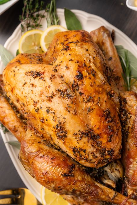 Whole roasted turkey garnished with fresh herbs and lemon slices on a white platter. Giblet Gravy, Thawing Turkey, Cooking Turkey Breast, Herb Roasted Turkey, Roast Turkey Recipes, Crockpot Turkey, Frozen Turkey, Oven Roasted Turkey, White Platter