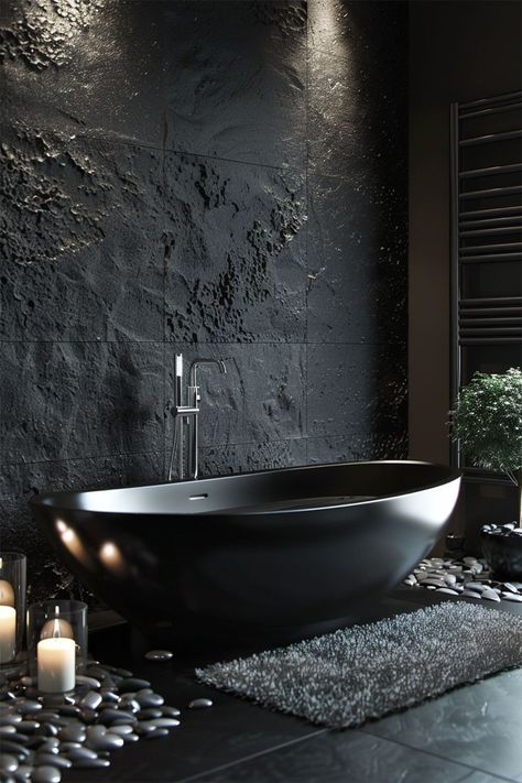 Luxurious Modern Bathroom • A sleek and modern bathroom showcasing a striking black freestanding bathtub against a textured dark stone wall, creating a bold and elegant contrast. • Ambient lighting highlights the unique wall texture and the smooth curves of the bathtub, adding depth and sophistication. • The floor is adorned with polished river stones and a chic gray rug, enhancing the spa-like feel of the space. • Strategically placed candles around the bathtub provide a soft, relaxing glow Dark Stone Bathroom, Modern Bathroom Black, Monochrome Home Decor, Monochrome Home, Dark Deco, Black Monochrome, Dark Bathrooms, Bathroom Black, Stone Bathroom