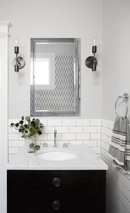 Soft gray walls are accented with white subway tiles finished with gray grout lined with a black washstand, Restoration Hardware Maison Powder Room Vanity, topped with honed carrera marble fitted with an oval sink and a polished nickel gooseneck faucet as well as an inset framed medicine cabinet illuminated by two light sconces. Black And White Powder Room, White Powder Room, Cabinet Restoration, Rehab House, Joseph Eichler, White Subway Tile Bathroom, Vanity Backsplash, Tile Backsplash Bathroom, White Marble Bathrooms