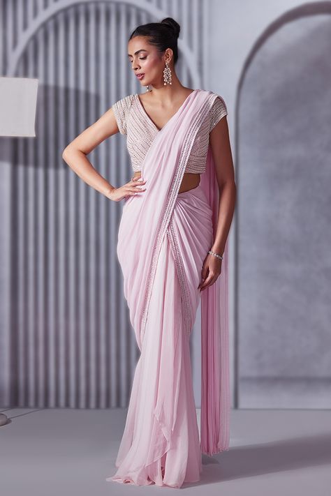 Pastel pink pre-draped saree with crystals, cutdana and sequins embroidered borders. Comes with a blouse.
Components: 2
Pattern: Embroidered
Type Of Work: Crystals, Sequins, Cutdana
Neckline: V Neck
Sleeve Type: Short
Fabric: Saree: Georgette, Blouse: Soft net, Lining: Shantoon
Color: Pink
Other Details: 
Heavily embroidered blouse
Attached lining
Length:
Saree: 44 inches
Blouse: 14 inches
Closure:
Saree: Side zip
Blouse: Back hooks
Occasion: Destination Wedding - Aza Fashions Short Sleeve Saree Blouse, Side Zip Blouse, Short Sleeve Blouse Design, Work Crystals, Saree Georgette, Draped Saree, Drape Saree, Georgette Blouse, Fancy Blouses