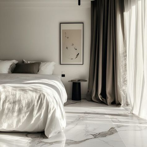 This elegant bedroom features luxurious granite materials with white marble flooring, adding sophistication to the space. The neutral palette of the plush bed and sleek decor, such as a black side table and abstract wall art, enhances the clean look. Soft natural light flows through sheer curtains, highlighting the refined use of building materials that create a warm, inviting atmosphere. White Marble Floor Bedroom, Bedroom Ideas Marble, Marble Floor Bedroom, White Marble Flooring, Building Materials Architecture, Sleek Decor, Plush Bed, White Marble Floor, Marble Flooring